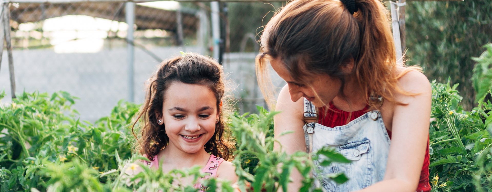 une-mère-et-sa-fille-regardent-des-plantes-au-jaridn-en-souriant