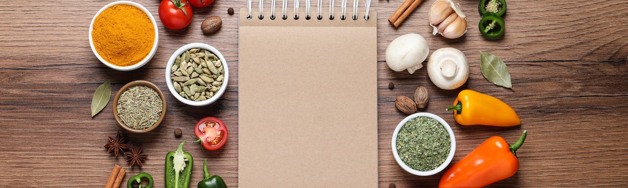 Ouvrez le livre de recettes et différents ingrédients sur une table en bois
